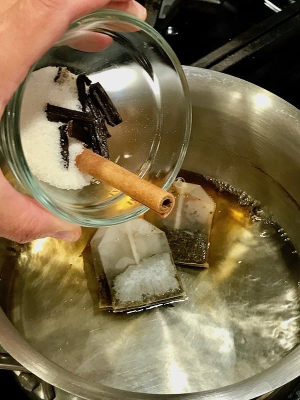 pouring spices into hot water with tea bags for chai latte | www.thefreshcooky.com