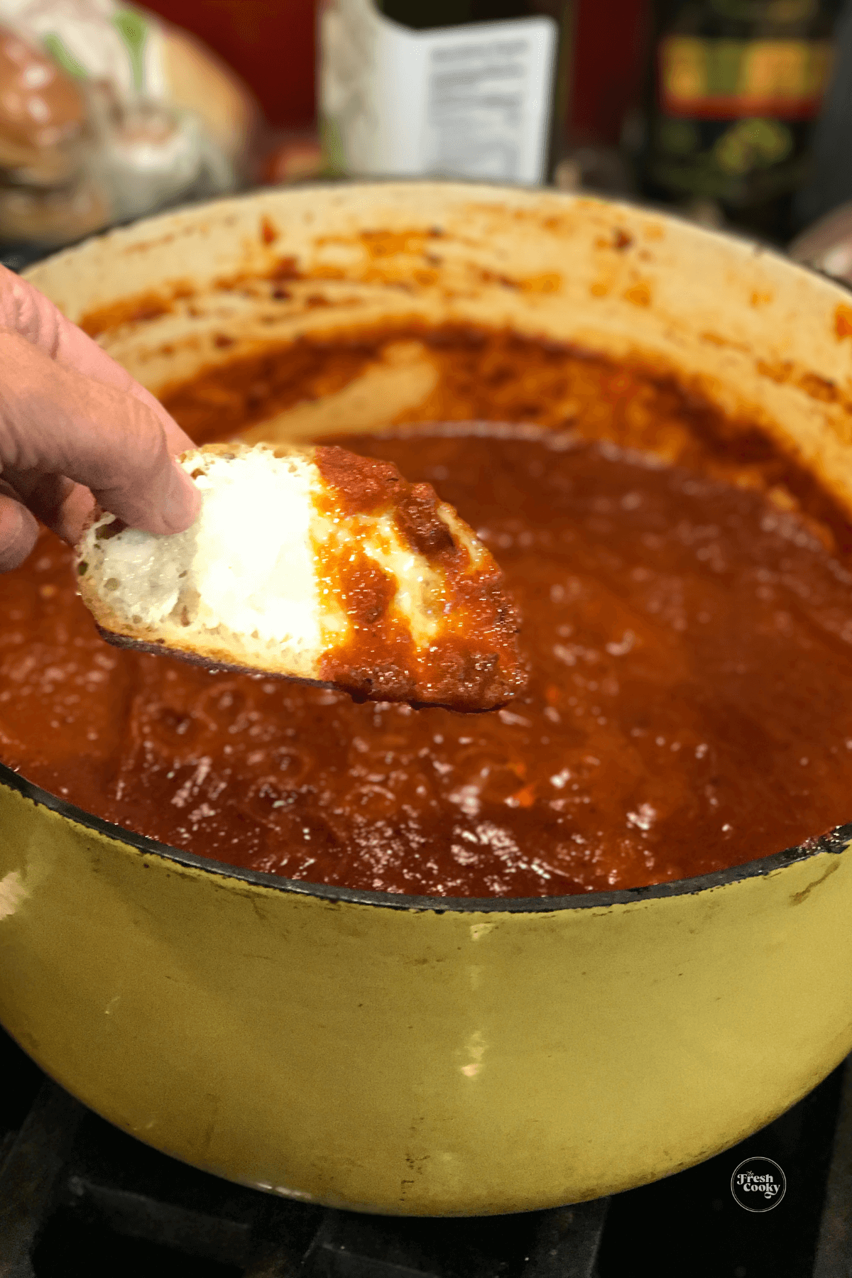 Hand dipping buttered Italian bread in rich, thick pasta sauce.