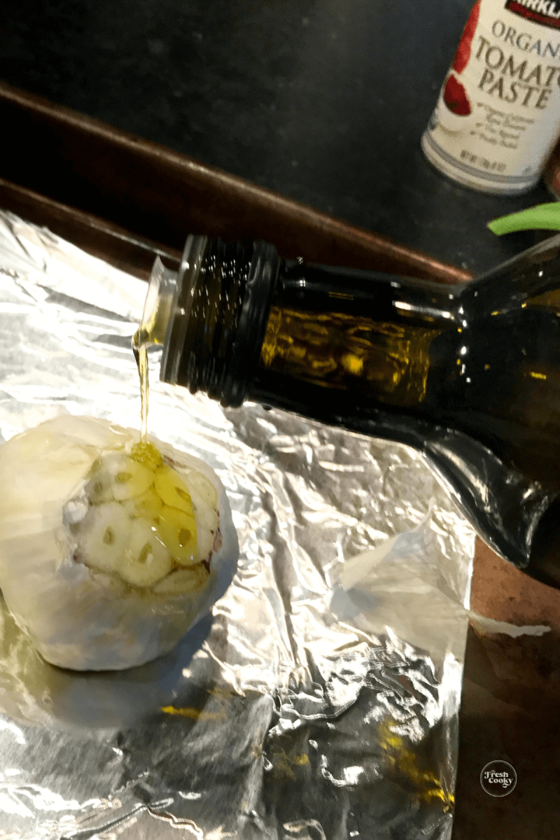 Drizzling garlic bulb with olive oil for roasting. 