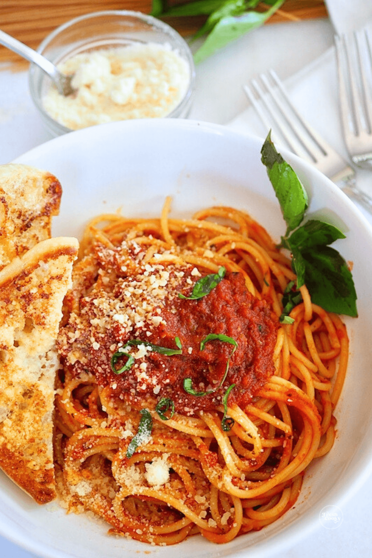 Bowl of spaghetti sauce with garlic toast and fresh toast.