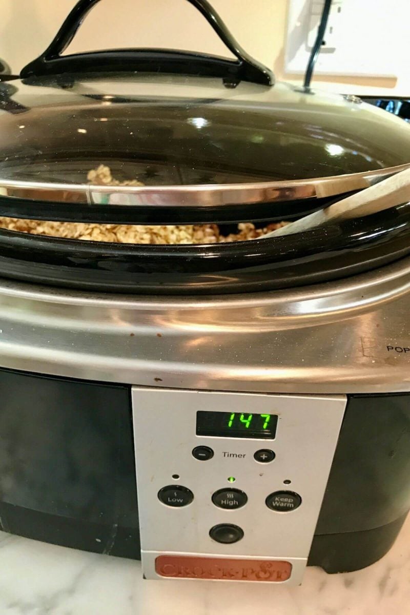 A wooden spoon venting the lid of a crockpot.