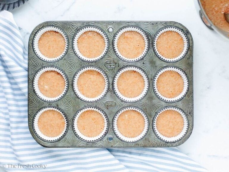 A cupcake tin filled with cupcake liners, and cupcake batter. 