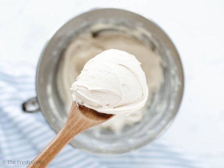 A wooden spoon full of creamy cream cheese frosting.