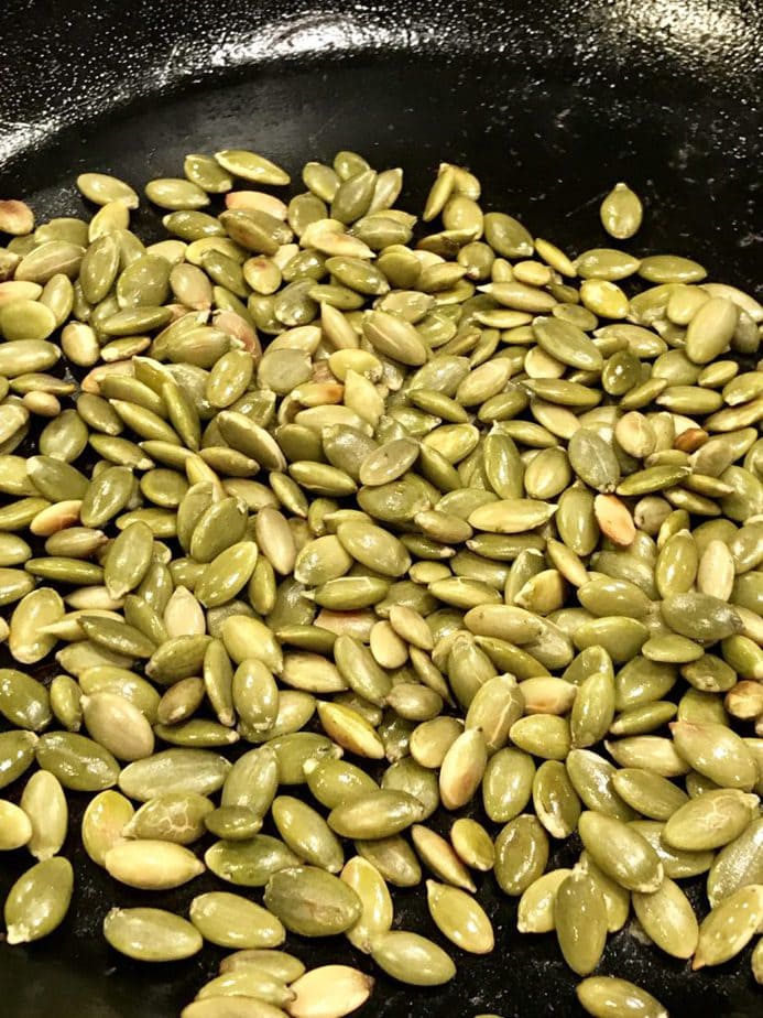 Close up image of toasted pumpkin seeds in fry pan. 