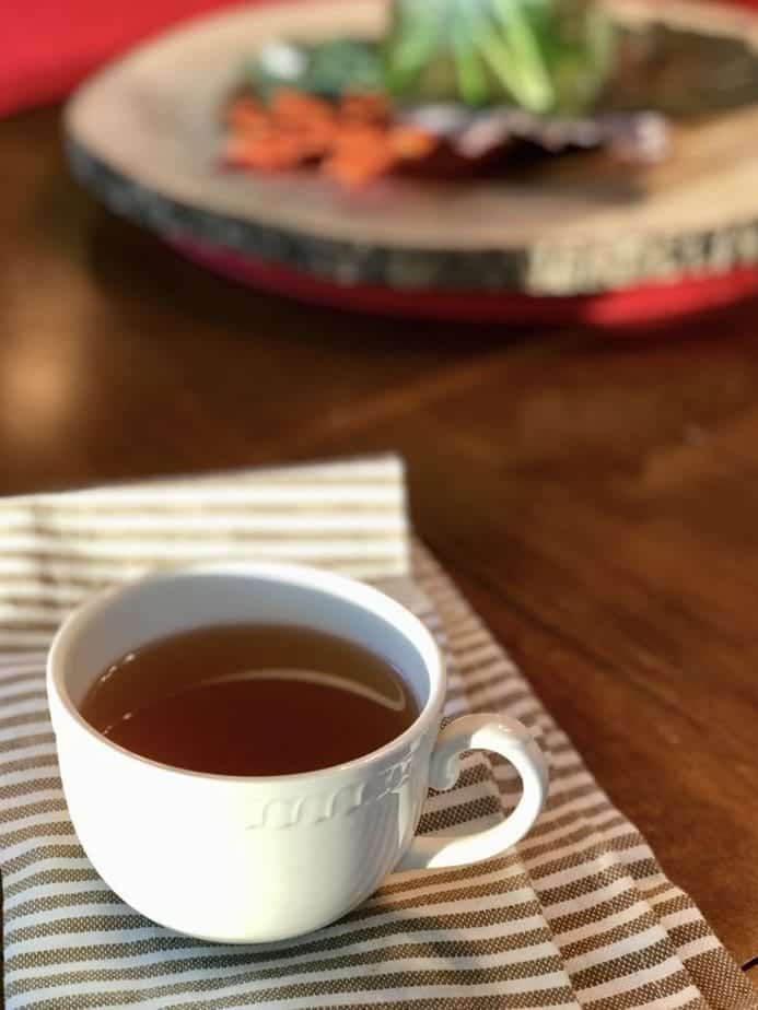 small mug of veggie broth on striped tea towel, sitting on table 