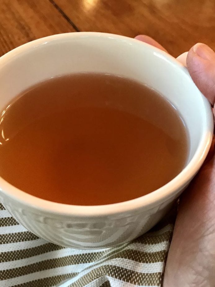 hand holding ivory mug with veggie broth