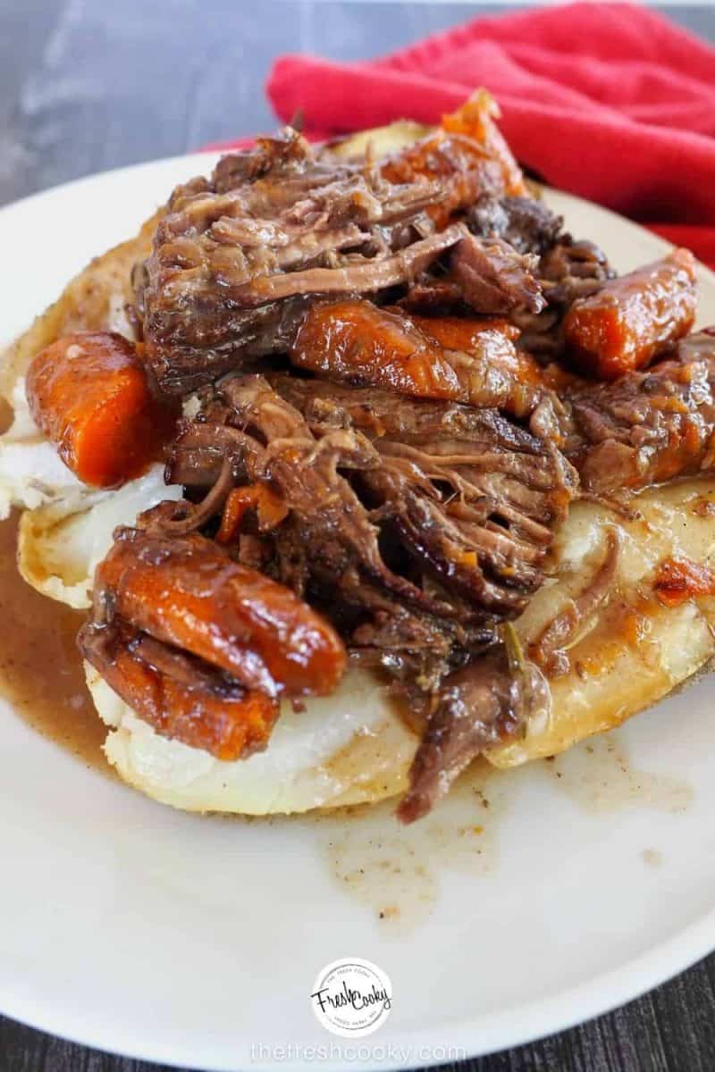 pot roast stuffed potato on a white plate with roast and carrots around.