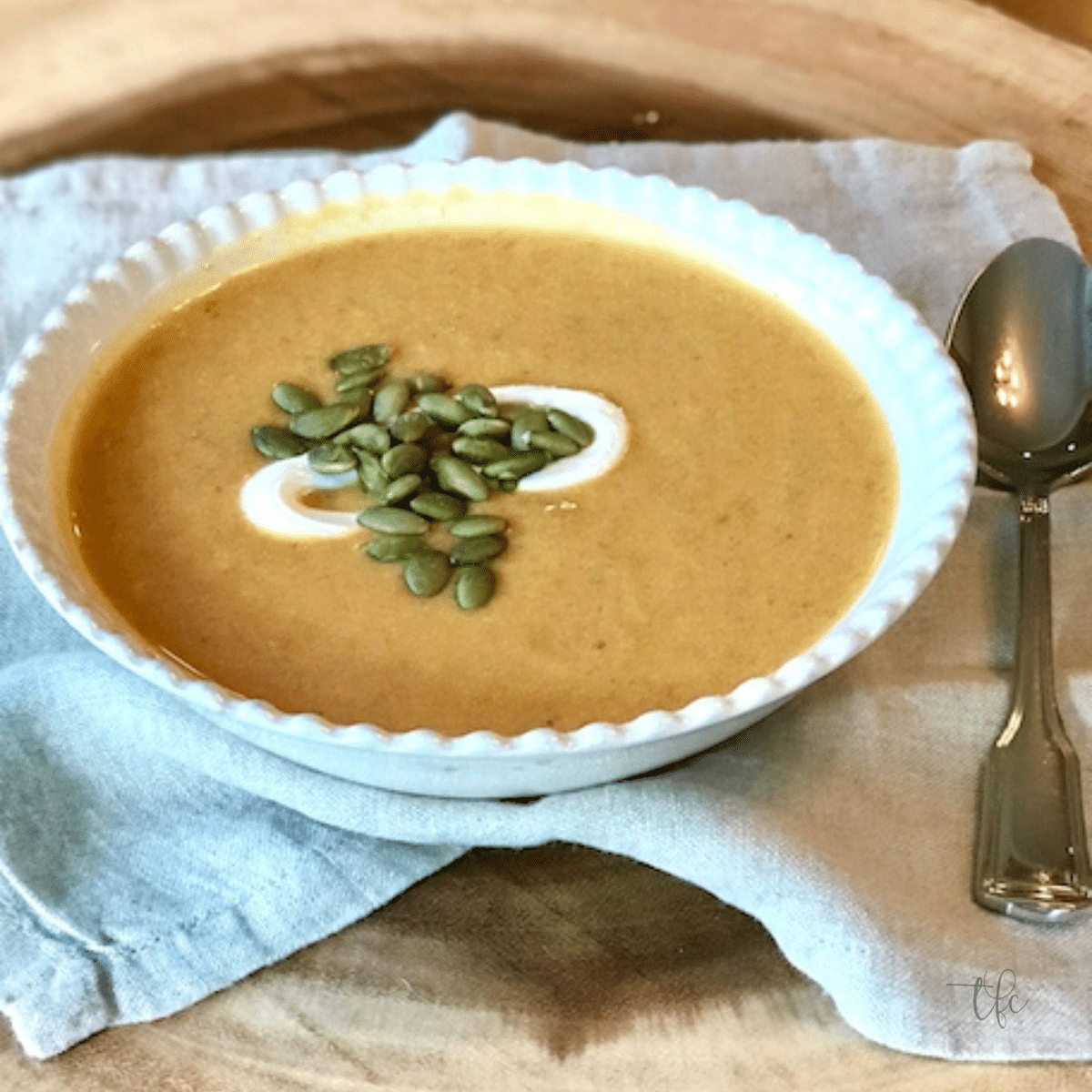 Easy Pumpkin Curry Soup in a pretty bowl with pepitas and creme fraiche for garnish.