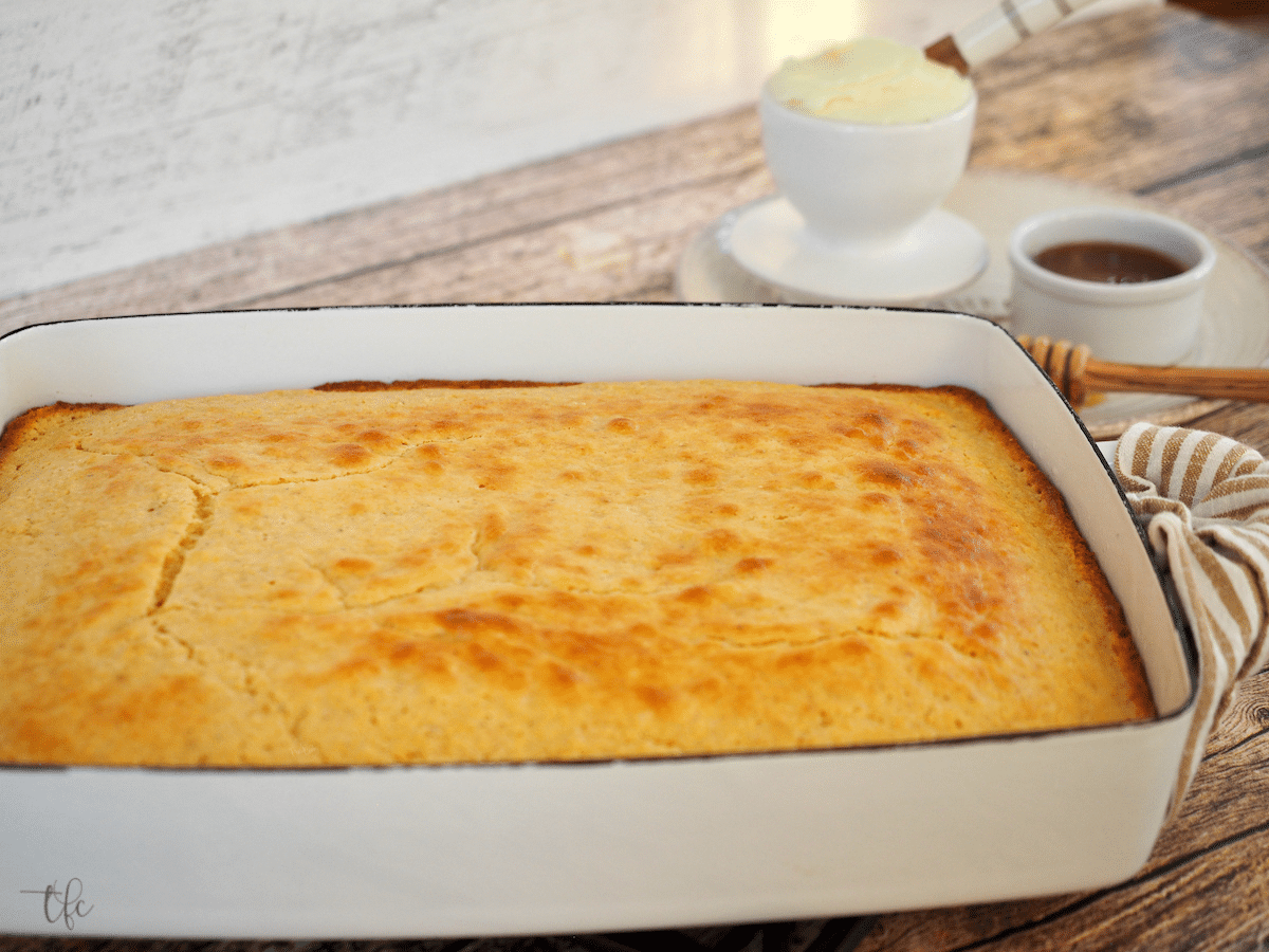 Sweet buttermilk cornbread recipe baked and in pan with butter and honey.