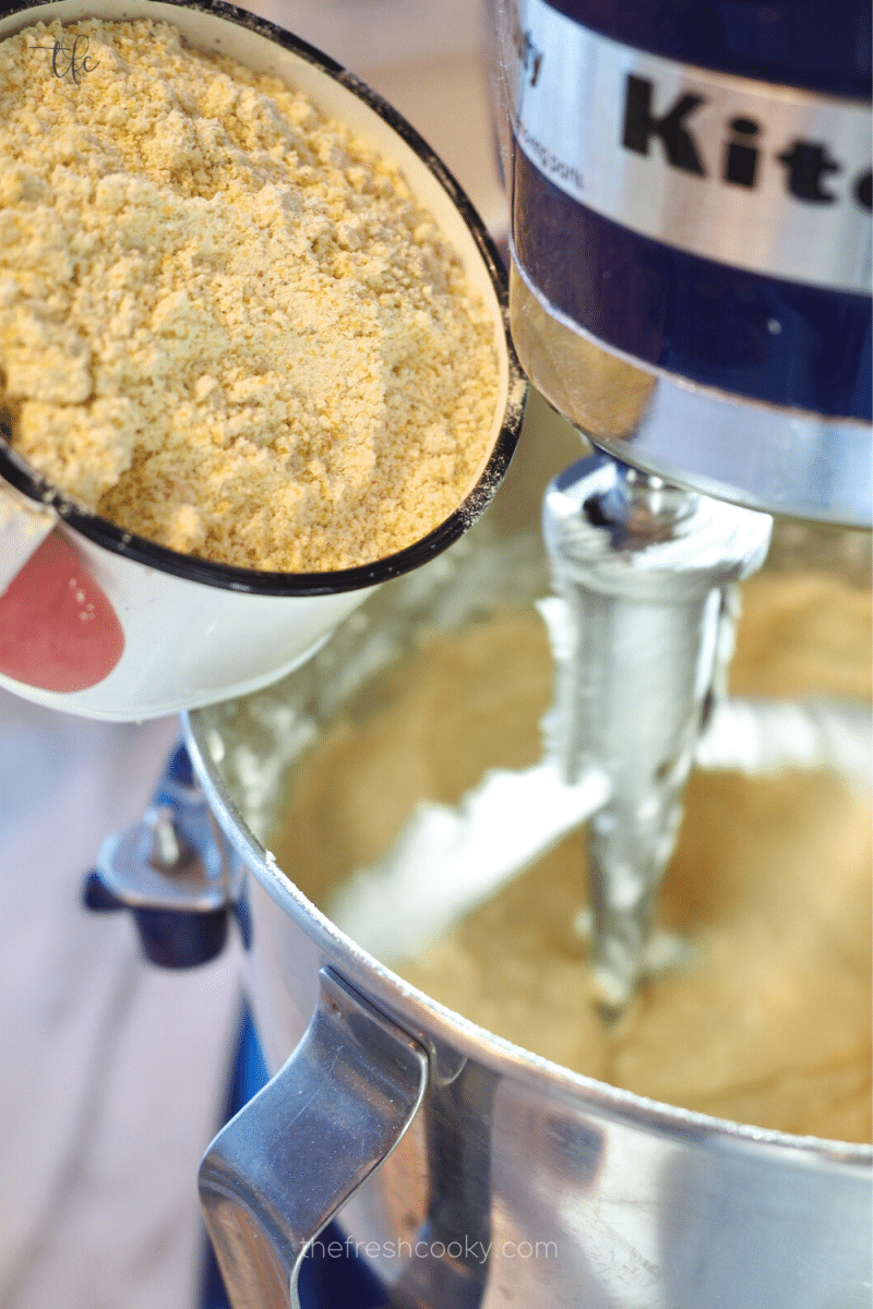 Pouring cornmeal into cornbread batter mixture. 