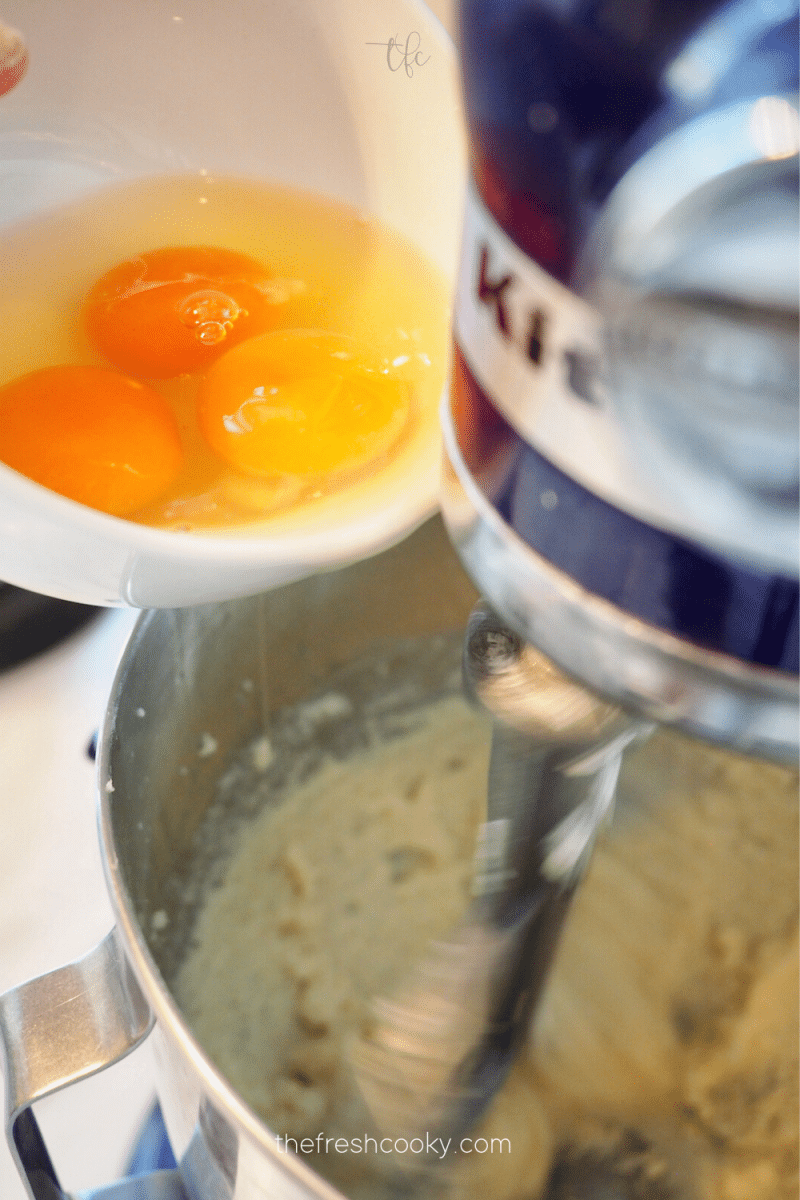 Adding 3 eggs to creamed sugar and butter mix for sweet cornbread recipe. 