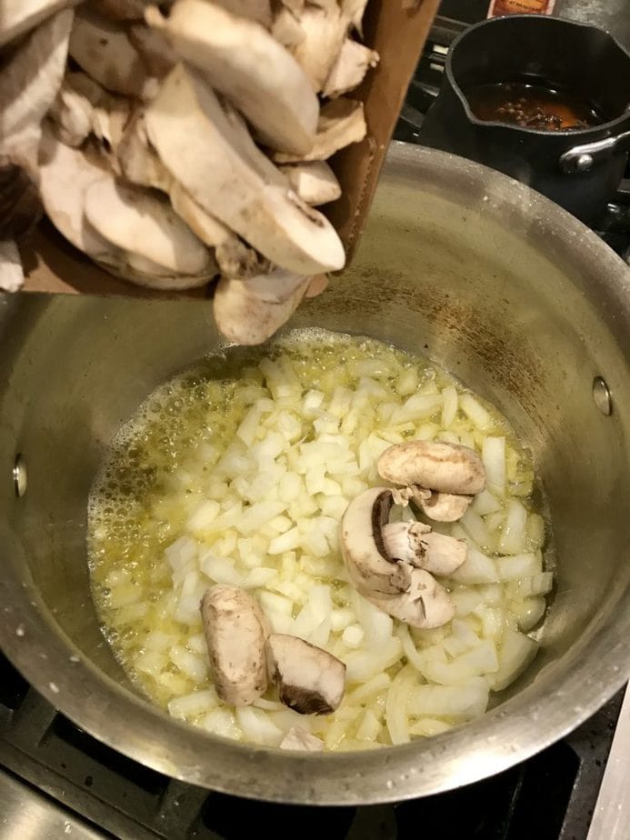 Tossing in sliced fresh mushrooms into butter and onions in a saucepan for sauteing.