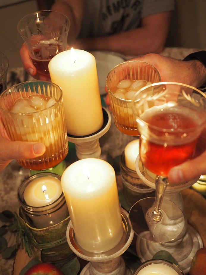 hands holding glasses and wine glasses toasting around the candles at Thanksgiving. 