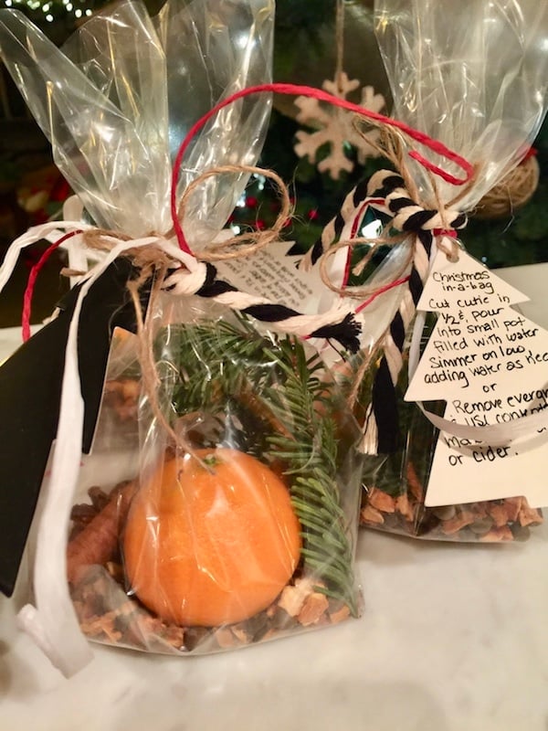 Christmas spices in a bag, with whole orange, spices and sprig of evergreen, tied with a bow and a label for how to use. 