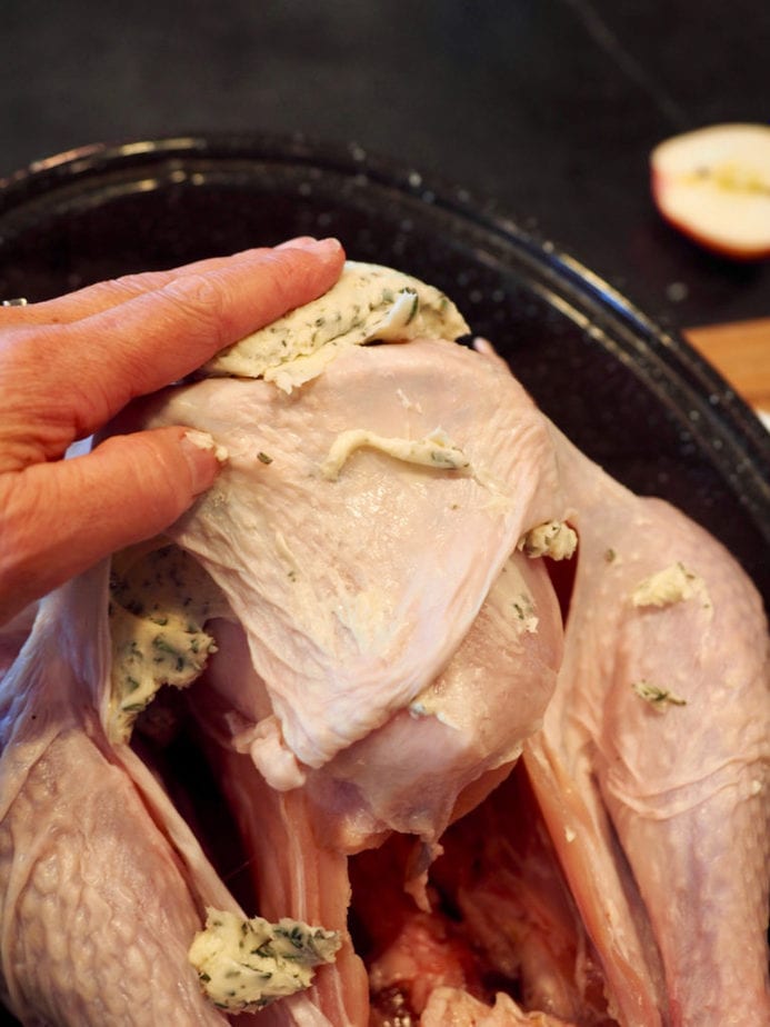 Hand rubbing herbed butter on top of turkey skin . Tender Turkey | www.thefreshcooky.com