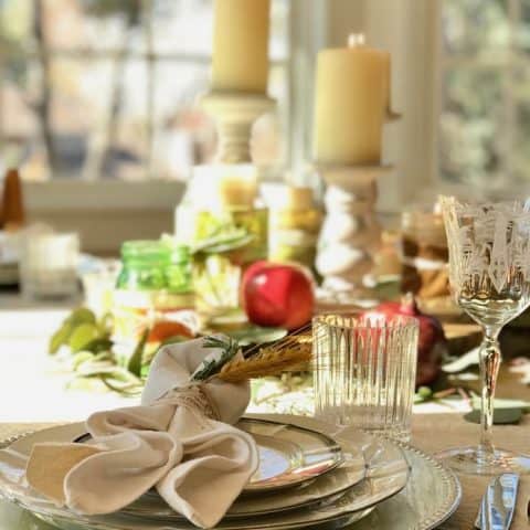 Image of thanksgiving table with candlesticks, china place settings, apples, natural decor and more.