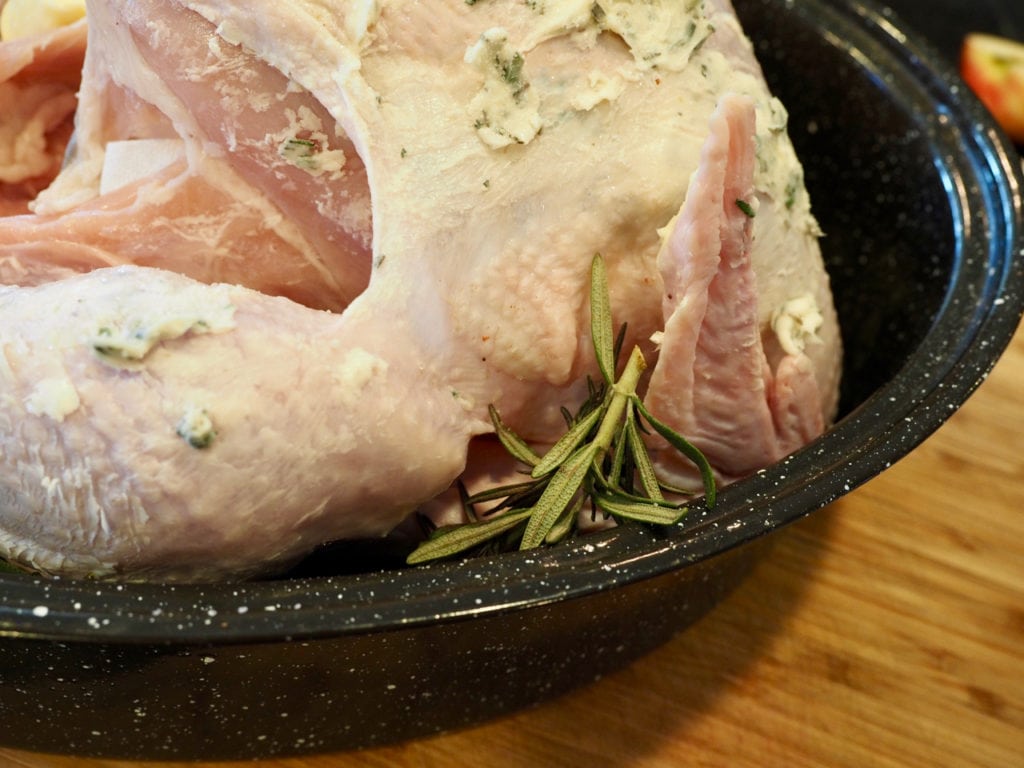 Whole turkey in roasting pan with sprigs of rosemary tucked around the sides. Tender Turkey | www.thefreshcooky.com