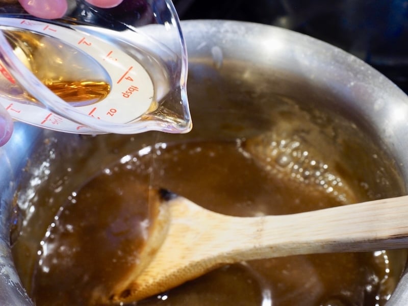 Pouring in bourbon to caramel sauce