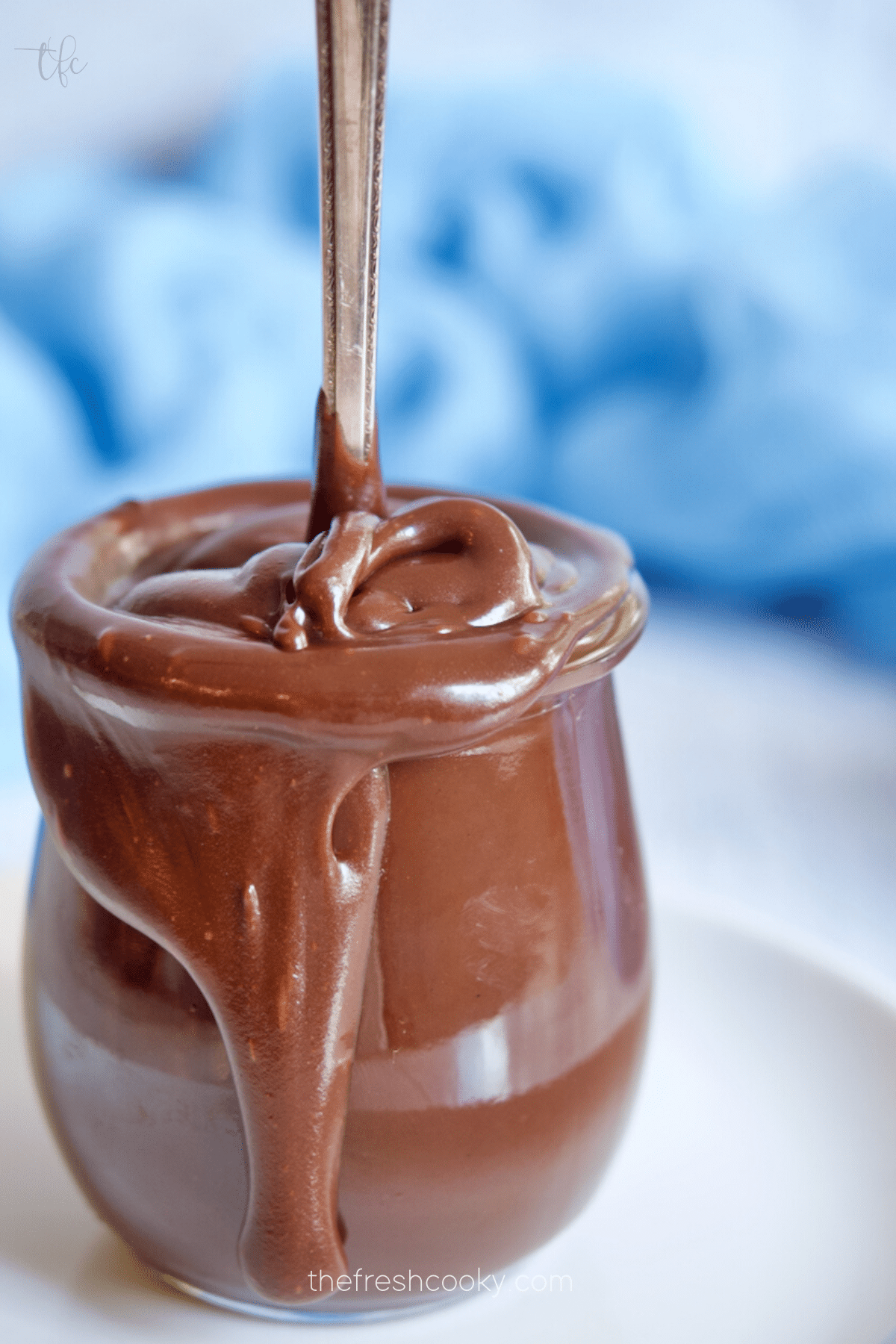 Old Fashioned Hot Fudge Sauce in glass jar with spoon standing up.