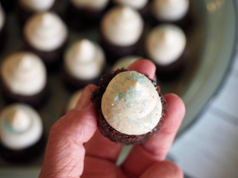 hand holding a frosting brownie bite with blue sprinkles. 