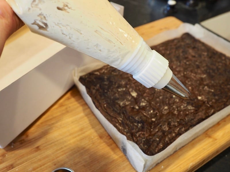 pastry bag fitted with piping tip ready to frost brownie bites