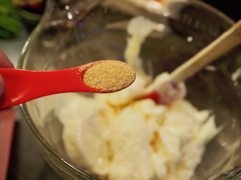 Adding garlic powder using a red measuring spoon. Artichoke Cheese Wontons | www.thefreshcooky.com