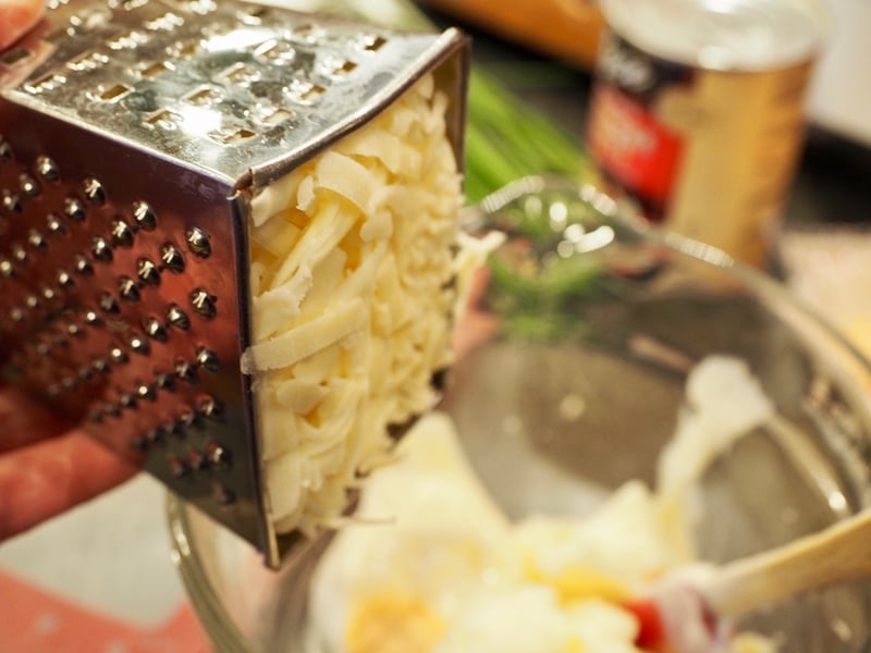 Shredded cheese in a grater going into mixture. Artichoke Cheese Wontons | www.thefreshcooky.com