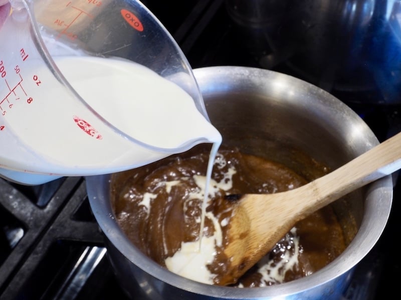 Pouring in heavy cream into sugar and butter caramel mixture