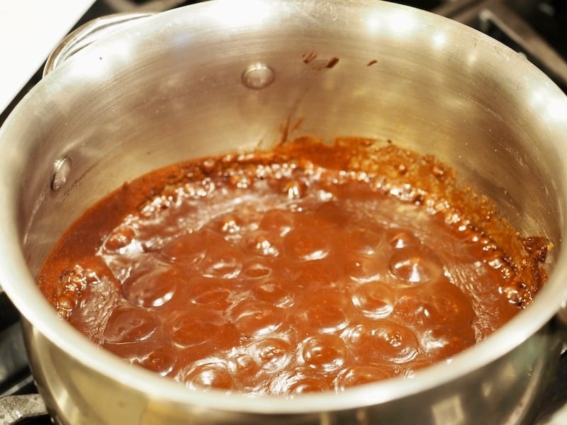 Big thick, bubbles of hot fudge sauce in saucepan. 