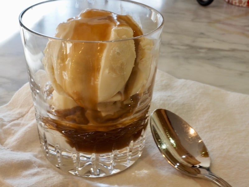 Vanilla Bourbon Caramel sauce over ice cream in a pretty glass with spoon