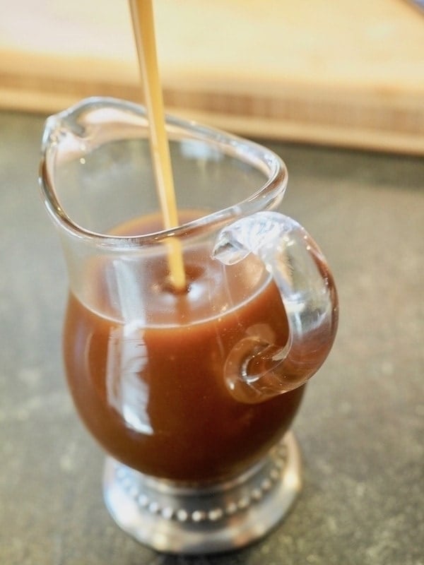 Small glass pitcher being filled with salted caramel bourbon sauce
