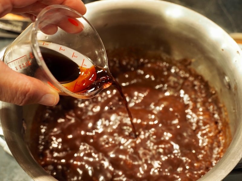 Pouring in using mini measuring cup pure vanilla extract.