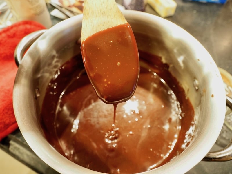 Thick hot fudge on back of wooden spoon. Chewy Hot Fudge Sauce.