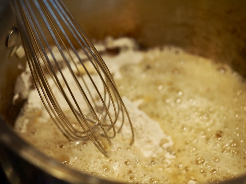 whisking flour into butter mixture to make a roux for broccoli cheese soup