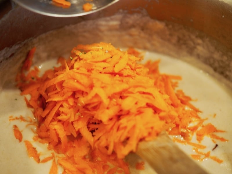 Shredded carrots in saucepan on top of thickened soup base.