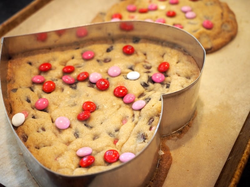 Baked cookie heart on pan still with form on top, sprinkled with new Valentine's M&M's. 