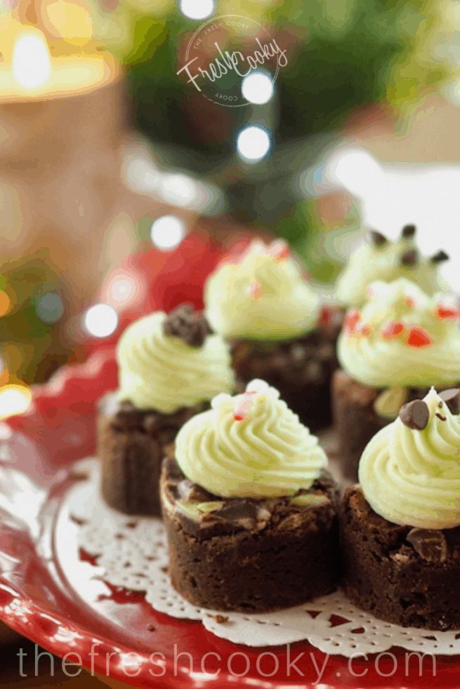 Holiday Mint Brownie Bites with kisses of minty buttercream on a red plate.   