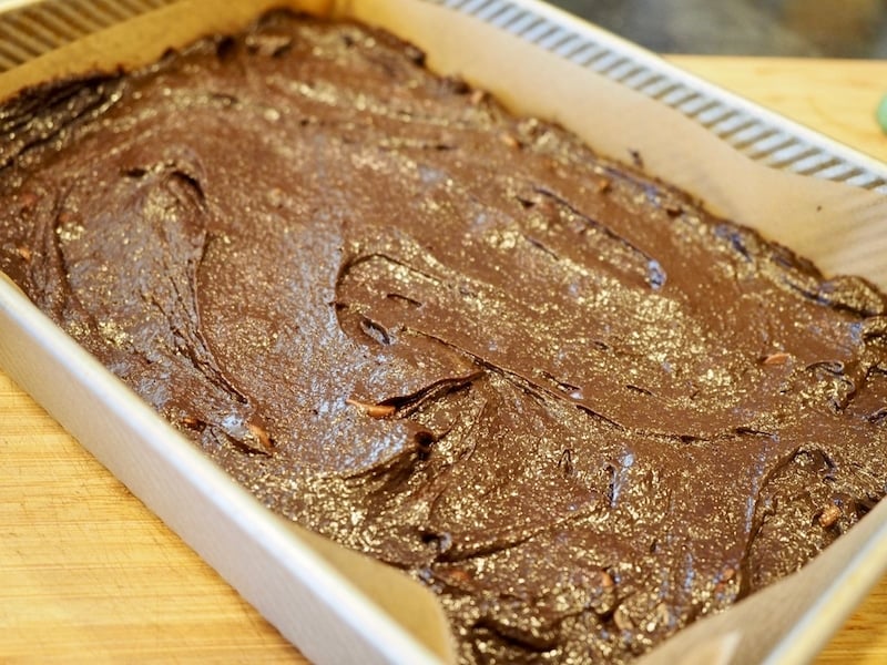 brownie batter spread into 9x13 inch pan lined with parchment paper