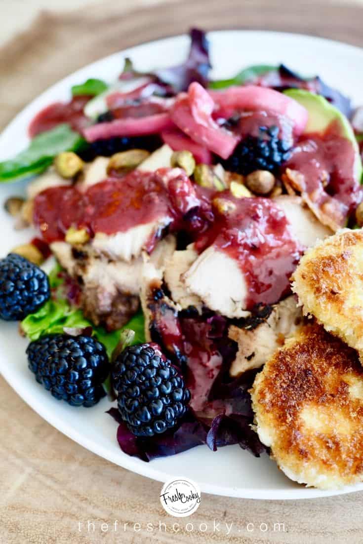 Close up of blackberry balsamic chicken salad with dressing, fresh blackberries and fried goat cheese. 