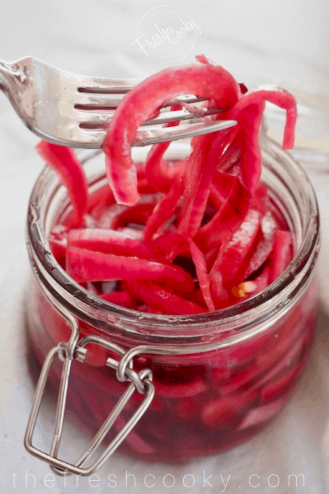 Sweet Pickled Red Onions in a jar with a fork.