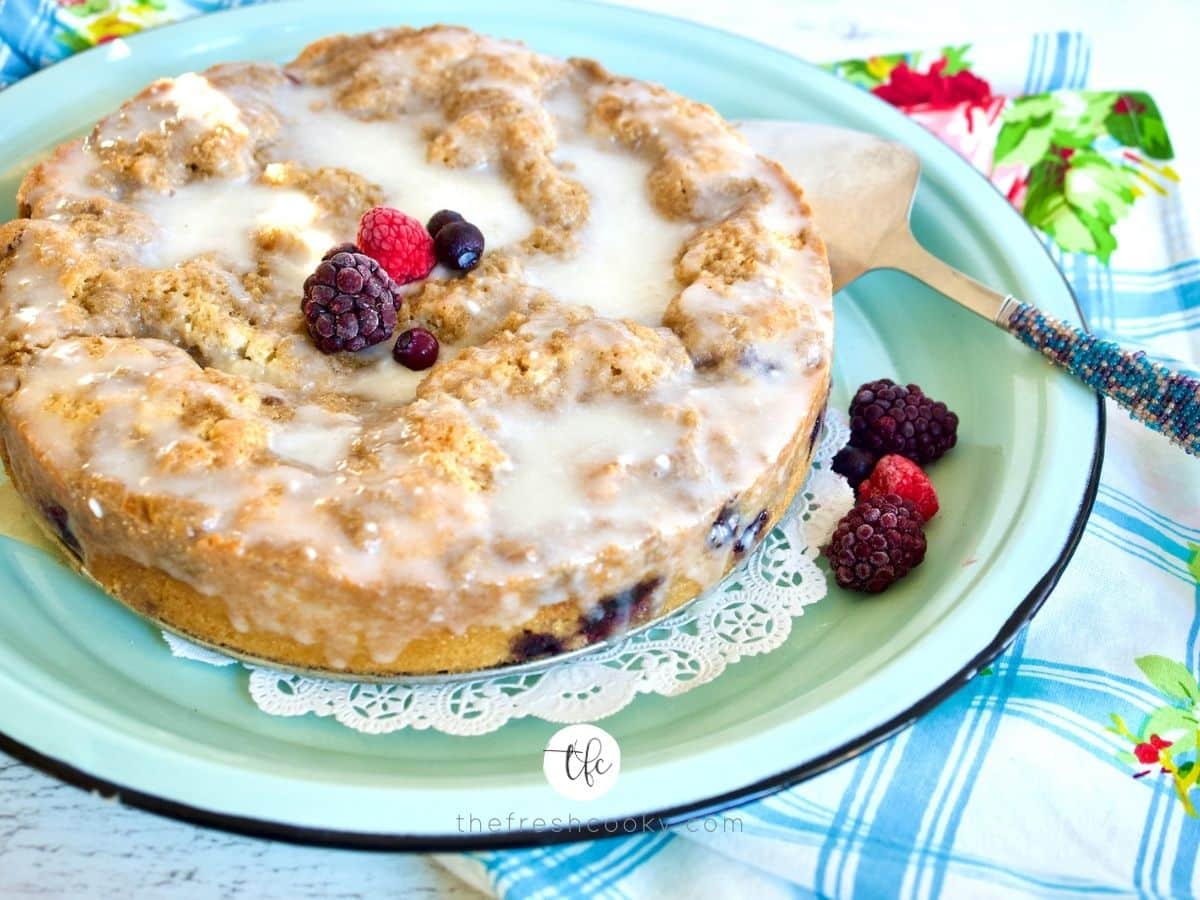 blueberry crumble cake facebook shot side view with frozen berries on top of cake.