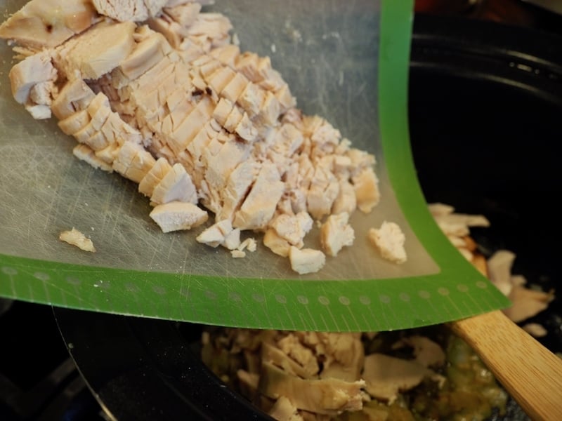 Adding diced cooked chicken on cutting board into crockpot. thefrehscooky.com 
