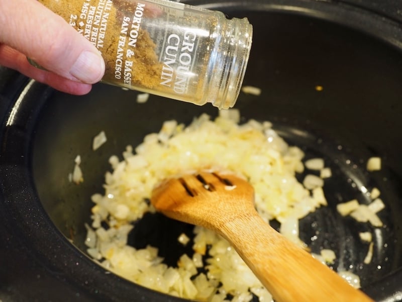 Sprinkling in Cumin into sauted onion mixture.