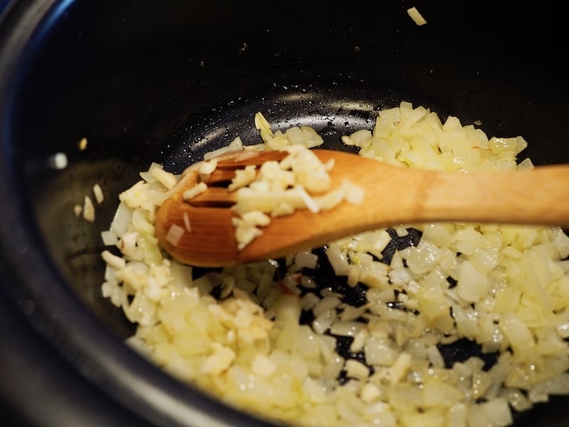 Garlic and Onions sauteeing in crockpot with wooden spoon. thefreshcooky.com 