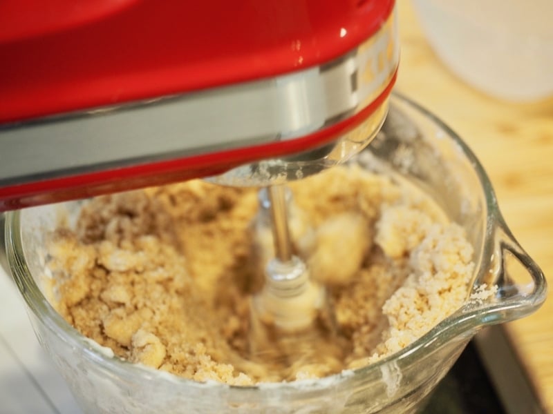 Glass mixing bowl with Red hand mixer mixing dough for streusel