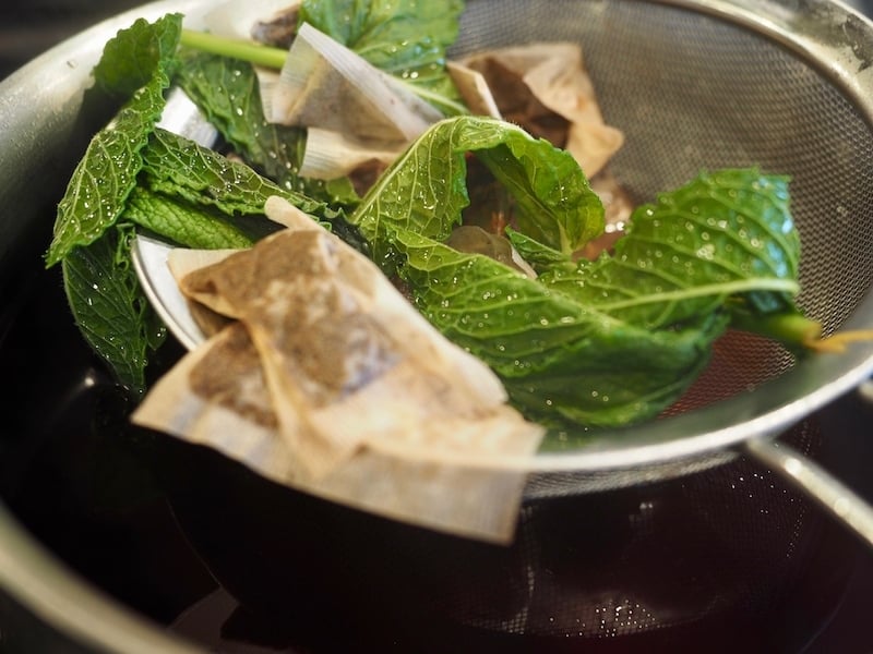 Using a fine mesh strainer to remove mint and tea bags. 