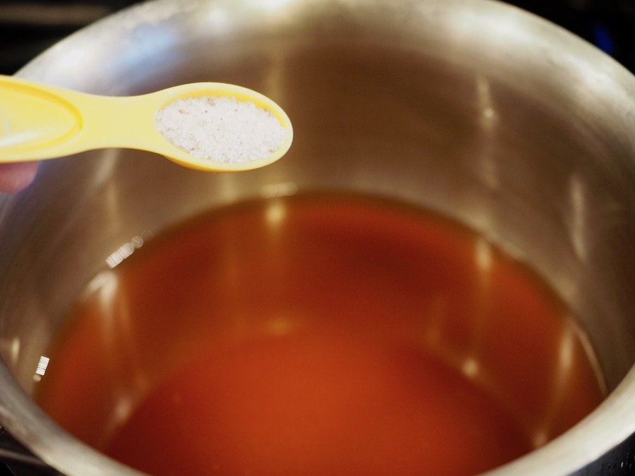 Adding kosher salt to pickling brine in pan. 