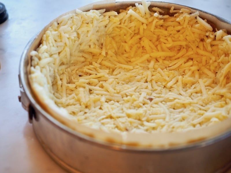 Close up shot of a hash brown crust in springform pan ready to bake. 