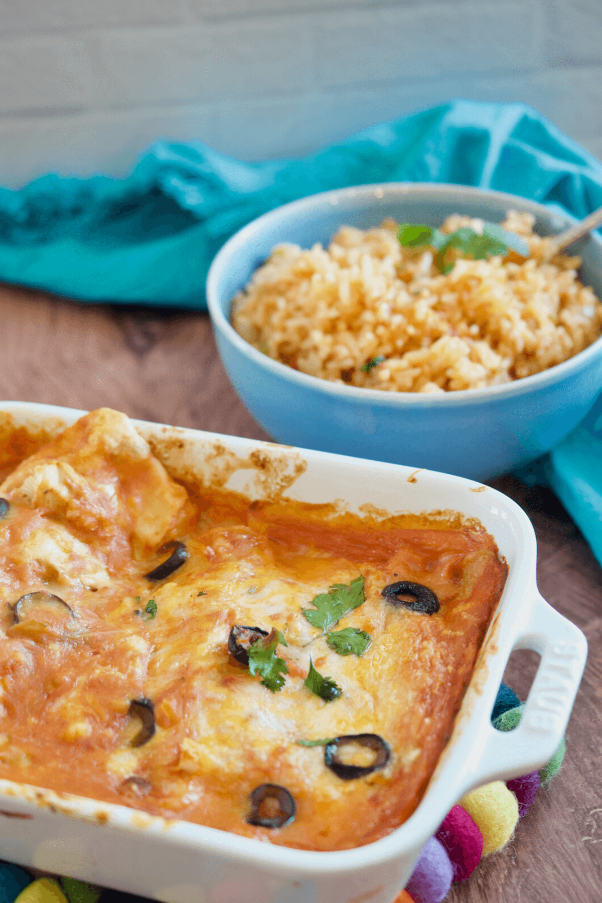 Cheese Enchiladas with old fashioned spanish rice in bowl behind.