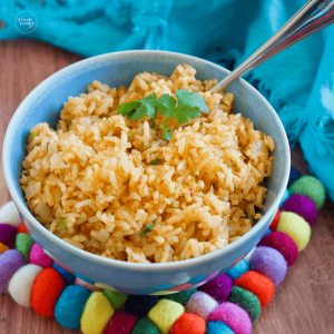 Square image of vegetarian spanish rice in bluebowl with colorful felted wool trivet.